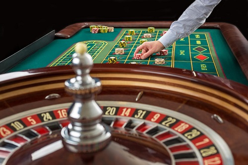 Roulette and piles of gambling chips on a green table in casino